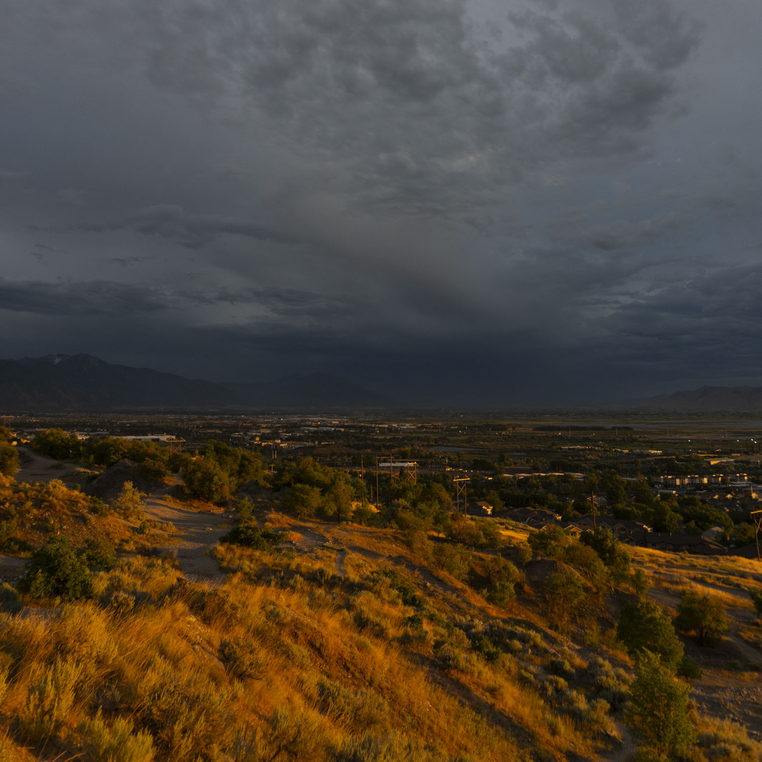 The sun about to set lights the mountain slopes brilliant gold contrasting with the shadowed town and landscape below